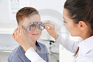 Children`s doctor putting trial frame on little boy in clinic.