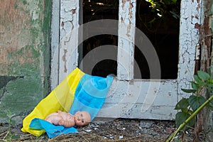 A children's doll lies on the flags of Ukraine in a blown-up house from missiles, the war in Ukraine, the death of
