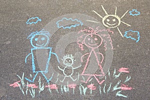 Children`s drawing with chalk on the asphalt, happy family: dad, mom and baby outdoors