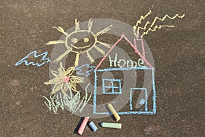 Children`s drawing with chalk on the asphalt: a house with the inscription home , sun and flower