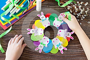 Children`s Easter gift wreath with colorful eggs and Easter bunnies. Paper, scissors, glue