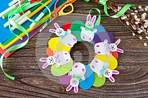 Children`s Easter gift wreath with colorful eggs and Easter bunnies. Paper, scissors, glue