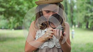 Children's education and curiosity. Closeup portrait of caucasian little girl in a straw hat looks at pine cone
