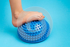 children& x27;s feet with a blue balancer on a light blue background, treatment and prevention of flat feet, valgus