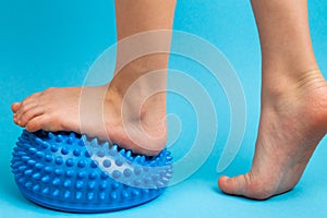 children& x27;s feet with a blue balancer on a light blue background, treatment and prevention of flat feet, valgus