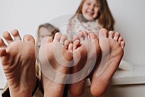 Children`s feet close up to the camera. Their blurred faces in a background.
