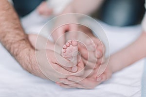 Children`s feet in the hands of parents