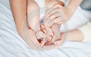 Children`s feet in the hands of parents