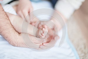 Children`s feet in the hands of parents