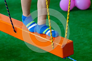 Children`s feet at the playground with swinging bridge