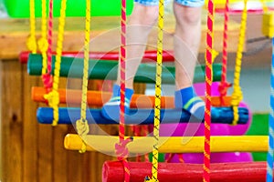 Children`s feet at the playground with swinging bridge