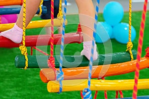 Children`s feet at the playground with swinging bridge