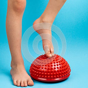 children& x27;s feet with a red balancer on a light blue background, treatment and prevention of flat feet, valgus