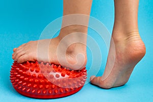 children& x27;s feet with a red balancer on a light blue background, treatment and prevention of flat feet, valgus