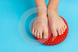 children& x27;s feet with a red balancer on a light blue background, treatment and prevention of flat feet, valgus