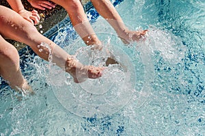 Children`s feet splashing in pool water photo