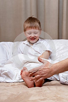 Children's feet under a blanket are tickled by dad's hand