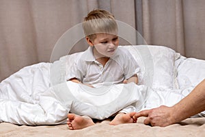 Children's feet under a blanket are tickled by dad's hand