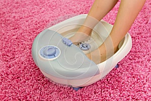 Children`s feet in a vibrating foot massager.