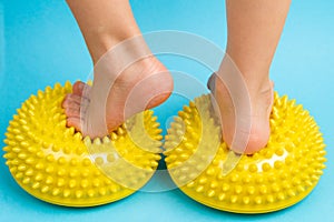 children& x27;s feet with a yellow balancer on a light blue background, treatment and prevention of flat feet, valgus