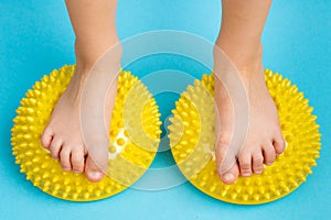 children& x27;s feet with a yellow balancer on a light blue background, treatment and prevention of flat feet, valgus