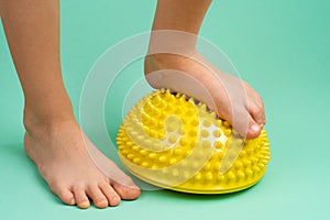 children& x27;s feet with a yellow balancer on a light green background, treatment and prevention of flat feet, valgus