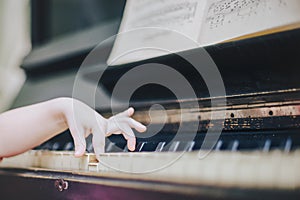 Children`s fingers on the keys of a piano playing.