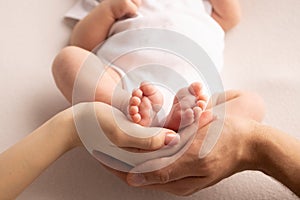 Children& x27;s foot in the hands of mother, father, parents. Feet of a tiny newborn close up. Little baby legs.