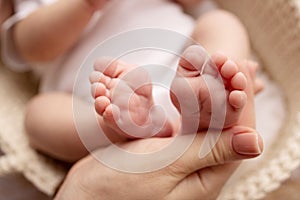 Children& x27;s foot in the hands of mother, father, parents. Feet of a tiny newborn close up. Little baby legs.