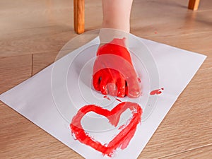 Children`s foot with a red heart.