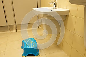 Children`s footrest near the sink in a public toilet. Concept - barrier-free environment