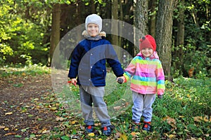 Children`s friendship. Children stand together and hold hands in the autumn park. Little boy and girl friends