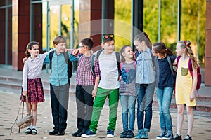 Children`s friendship. Schoolmate students stand in an embrace on the schoolyard.