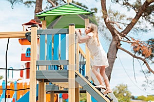 Children`s games. The little girl with the effort of climbing the stairs to the wooden tower game