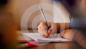 Children's hand close-up. the child uses a pencil to practice writing letters. The child learns to write in a notebook
