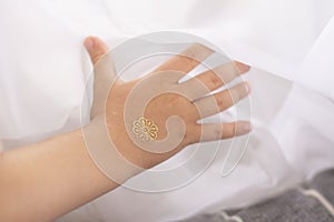 Children`s hand with a gold tattoo is touching the curtain. Light, airy curtain, bright gentle light.