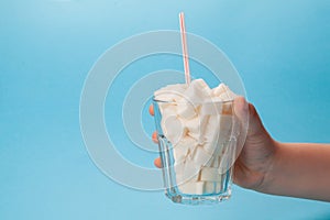 Children's hand holds a glass glass with a tube full of sugar cubes