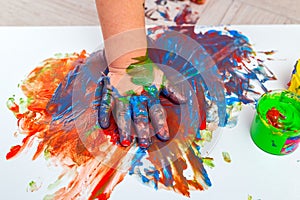 Children`s hand in paints. Finger paints. baby Artwork . Flat lay photo