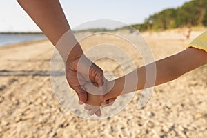Children& x27;s hand and palm in daddy& x27;s hand on beach on sunny day.