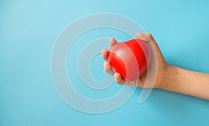 children's hand squeezes a red heart toy on a blue background, blood donation theme, first aid for childre