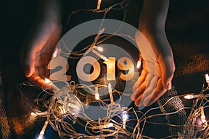 Children`s hands on a blanket with a shiny garland and numbers 2019, on the eve of the new year
