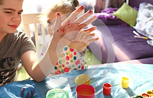 Children`s hands boy and girl in paints. Brother and sister draw at home. Creative concept. Childhood. Mess at home