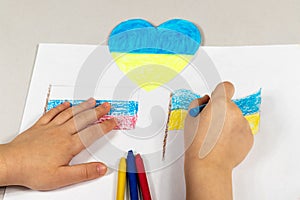 Children& x27;s hands of a child draw the flags of Ukraine and Russia close-up. View from above. Children against war