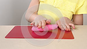 Children`s hands close-up roll plasticine on the Board. Children`s play with plasticine. Children`s creativity and