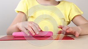 Children`s hands close-up roll plasticine on the Board. Children`s play with plasticine. Children`s creativity and