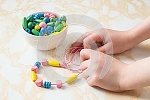 Children's hands collect beads on a string