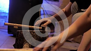 Children`s hands compete in hammering nails into a stump, close-up