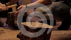 Children`s hands compete in hammering nails into a stump, close-up