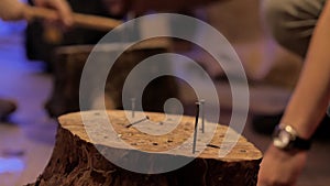 Children`s hands compete in hammering nails into a stump, close-up