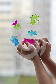 Children`s hands decorating a window glass for Christmas